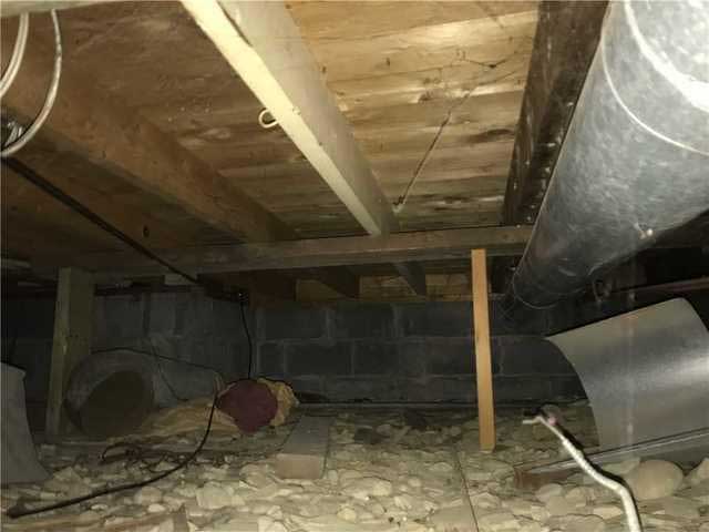 Crawl space with loose old insulation before sealing